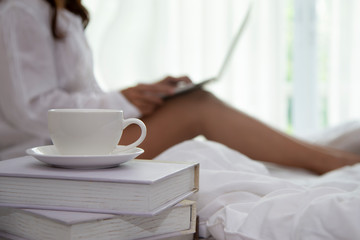 Close up on coffee cup with blurred relax  woman using laptop