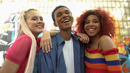 Multiracial group of teenagers looking camera on graffiti wall background, style