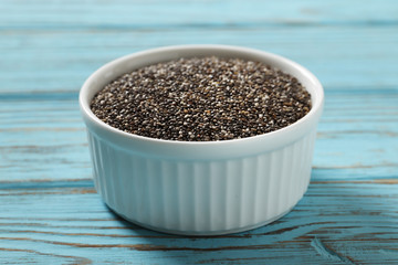 Chia in a white ceramic bowl on a blue wooden background.