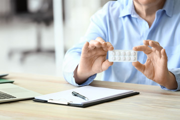 Elderly man with pills in office