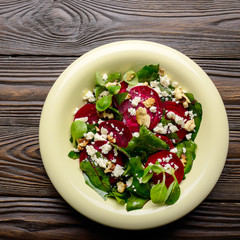 Top view at mediterranean roasted beet salad with walnuts feta cheese and mash leaves on wooden table