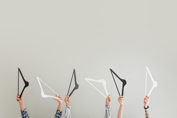 Female hands with clothes hangers on light background