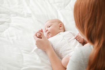 Mother with cute baby lying on bed