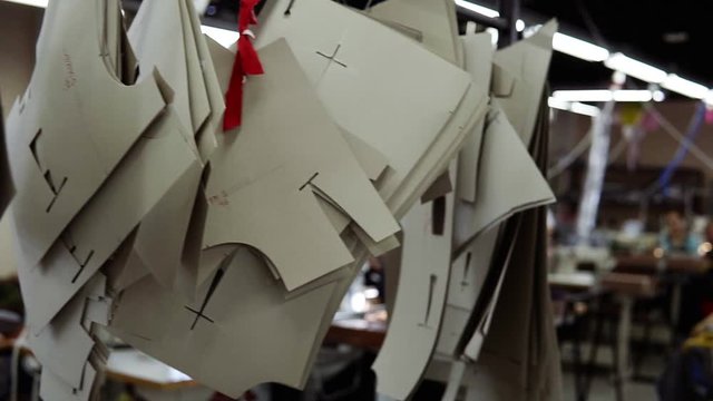 Close-up overview of stencils patterns hang in the tailor studio. Samples used in clothes design, tailoring. Picture of tailor studio with females workers in process