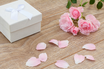 Gift box with rose flowers on the wooden background.