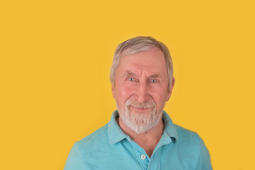 Elder man with beard and grey hair tricky smiling over yellow background