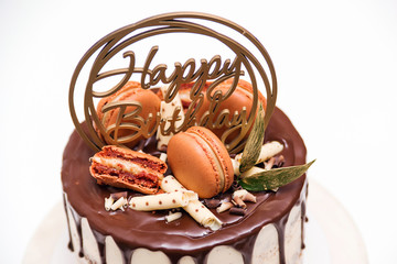 Birthday cake decorated with golden macaroons, top view. Elegant naked cake topped by chocolate. Birthday party celebration