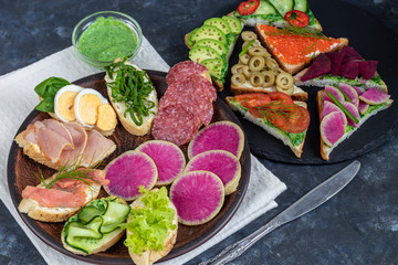 Sandwiches are triangular and oval. Vegetarian and more. Dressing with avocado and spinach and creamy yogurt. Top cucumber, turnips, tomatoes, salami, balyk, red caviar, spinach, eggs and olives. 