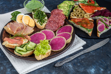 Sandwiches are triangular and oval. Vegetarian and more. Dressing with avocado and spinach and creamy yogurt. Top cucumber, turnips, tomatoes, salami, balyk, red caviar, spinach, eggs and olives. 