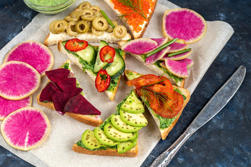 Sandwiches are triangular and oval. Vegetarian and more. Dressing with avocado and spinach and creamy yogurt. Top cucumber, turnips, tomatoes, salami, balyk, red caviar, spinach, eggs and olives. 