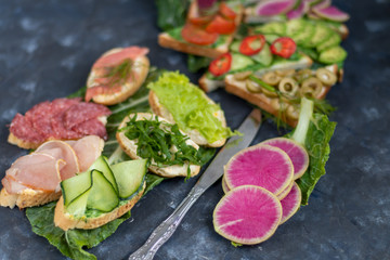 Sandwiches are triangular and oval. Vegetarian and more. Dressing with avocado and spinach and creamy yogurt. Top cucumber, turnips, tomatoes, salami, balyk, red caviar, spinach, eggs and olives. 