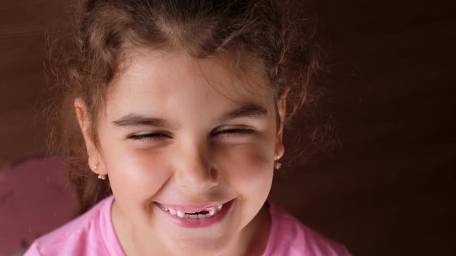 Portrait of a baby girl with a toothless smile. The child laughs hard. Show no teeth.
