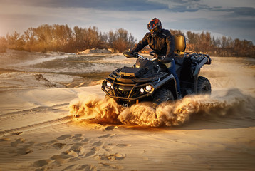Racing powerful quad bike on the difficult sand in the summer.