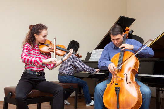 Family trio rehearsing. Father plays the cello, daughter is a violinist, mother plays the piano