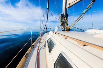 White sloop rigged yacht sailing in an open Baltic sea on a clear sunny day. A view from the deck...