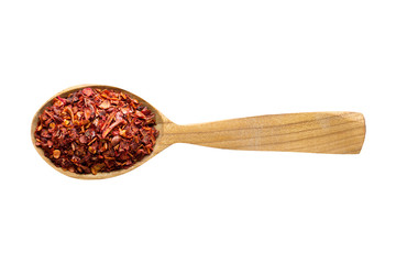 chili pepper flakes in wooden spoon isolated on white background. spice for cooking food, top view.