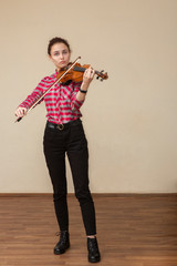 A photo of a young gir playing violin. Young violinist prepares for lesson.