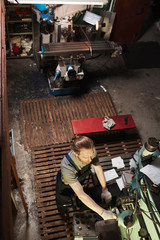 Fototapeta na wymiar High angle view of mechanic working on lathe with tools in the warehouse