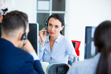 Beautiful consultant of call center in headphones.  Portrait of smiling female customer using headset at call center office