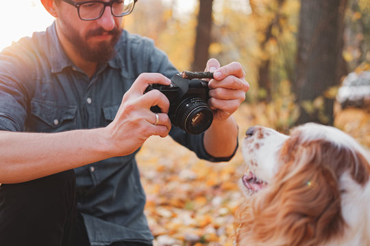 Man taking a photo of his dog in the park. Male photographer working with a dog outdoors
