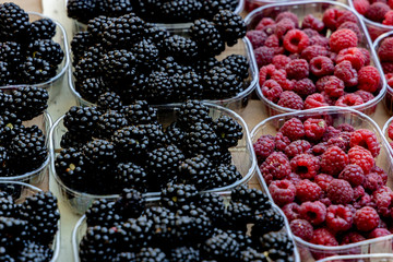 Raspberries and blackberries in small containers at a farmer's market.