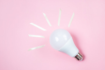 LED lamp lies on a pastel pink background. Nearby - pieces of satin yellow ribbon symbolize the...