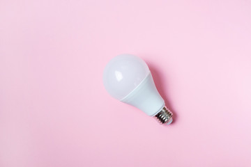 LED light bulb lies on a pastel pink background. Energy saving concept. Minimalism, top view, flat...