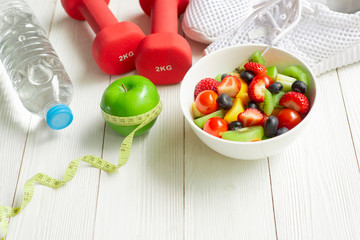 Healthy  food  concept , green apple with measuring tape with salad in bowl water dumbbell running shoes on white wood background  ,  eating lifestyle - Powered by Adobe