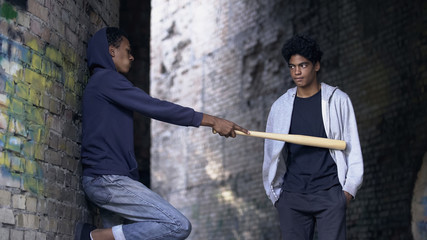 Obraz na płótnie Canvas Black young criminal with bat demanding money on abandoned street, extortion