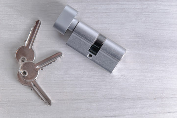 Lock core and door keys on a light background. Repair in the house. Installing a new lock on the...