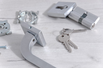 The core of the lock, handles and door keys on a light background. Repair in the house. Installing...