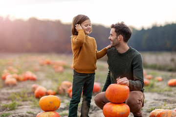 Father and son in pumpkin patch field