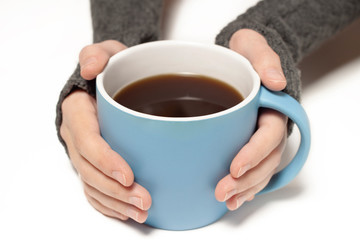 Holding big blue cup with tea, coffee in hands wearing mitts view infront