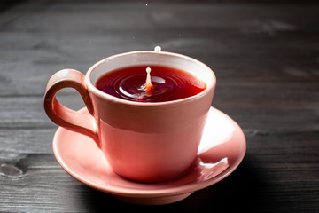 Cup of Tea with a drop of milk on wooden background