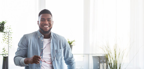 Portrait of smiling black guy with glasses in hands