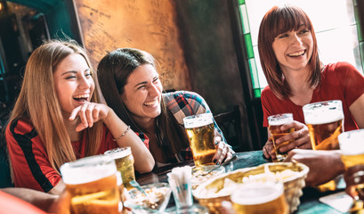 Happy women best friends drinking beer at vintage bar restaurant - Female friendship concept with...