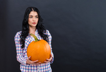 Young woman holding a pumpkin on a black background