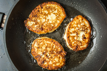 Appetizing cheese curd pancakes fried in oil pan.