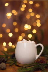 Obraz na płótnie Canvas Cacao drink in a white cup with marshmallow on the background of bokeh lights, Hot Christmas drink