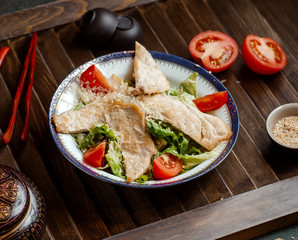 caesar salad with chicken breast fillet garnished with grated parmesan