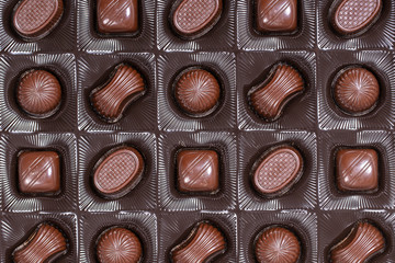 Brown chocolate candy background. Assortment of chocolate candies sweets in the box