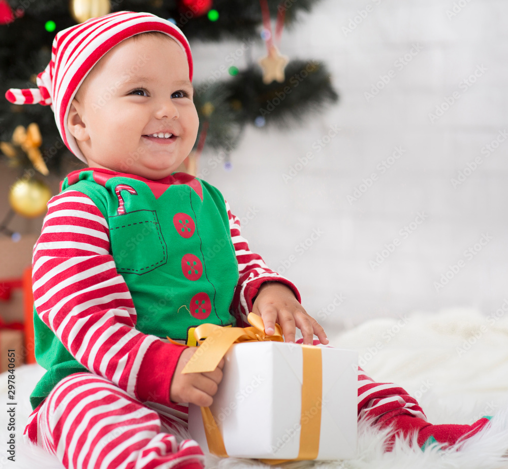 Wall mural Happy baby elf playing with with Xmas gift at home