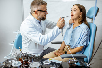 Senior otolaryngologist making oral flushing procedure for a young patient at the ENT office