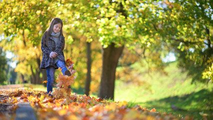 Cute little girl with her hair walks in a beautiful park collects a bouquet of leaves and dreams