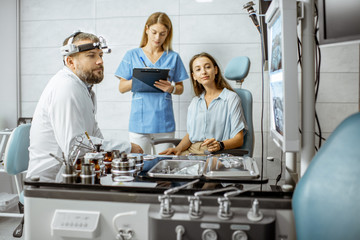 Patient with senior otolaryngologist and female assistant in ENT office during a medical examination, looking on x-ray head image