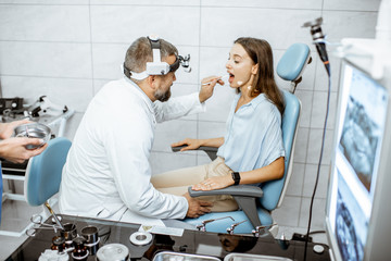 Patient with senior otolaryngologist in ENT office during a medical examination, doctor examining throat