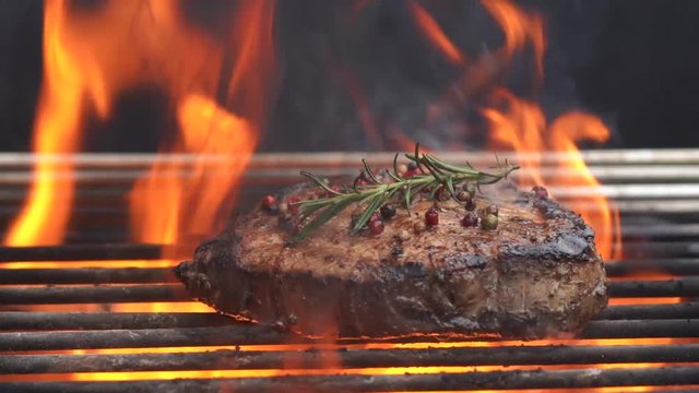 Cooking meat cutlet and  Rosemary Pepper  Salt  on hot grill barbecue grate with fire flams and smoke on black background.