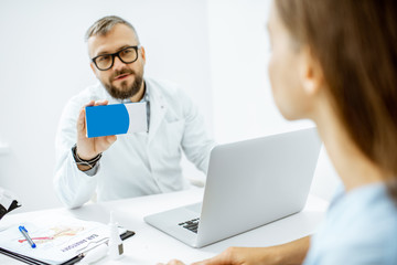 Senior doctor offering some medicine for a young patient, holding box with blank space to copy paste in the medical office