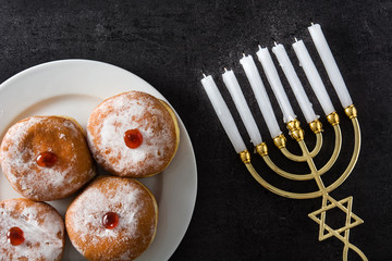 Jewish Hanukkah menorah and sufganiyot donuts on black background
