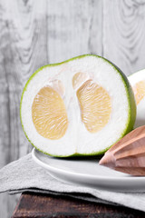 Oroblanco fruit cut into halves on a ceramic plate on the edge of the wooden table